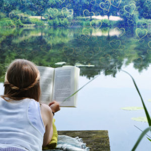 Lesbian woman reading a romance novel at a lake